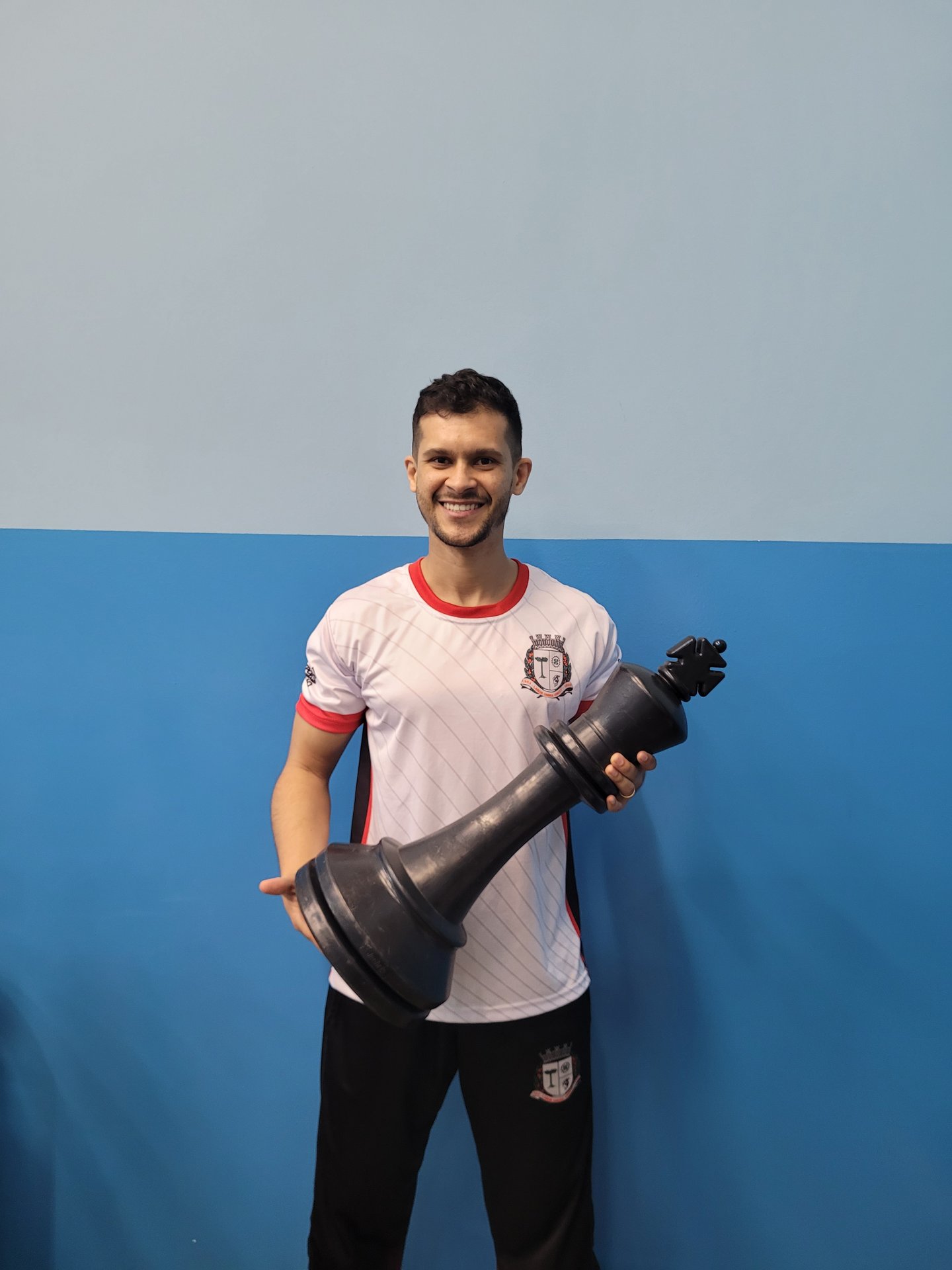 André segurando peça de rei gigante do Xadrez Taboão